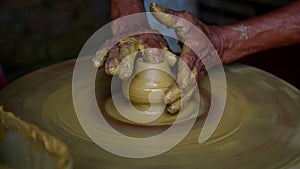 Close view skilled asian master makes pot with yellow clay