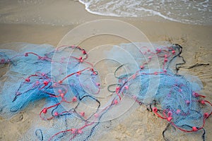 Close view of some blue fishing net floaters on the beach with boat and human while laying nets on the sea