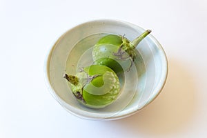 Close view of two round green Thai eggplant Solanum melongena in a shallow bowl