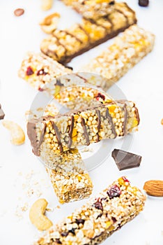 Close view of various homemade granola bars with nuts, seeds, dark chocolate, honey and berries over a white background