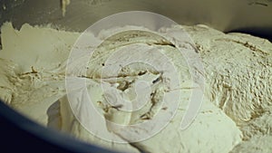 Close view of wheat dough in an automatic kneader. Equipment process on bakery