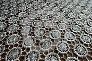 Close view of white crochet lacy fabric on wood