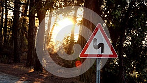 Close view of winding road sign on white background in red frame. triangular sign with warning of curvy road in forest