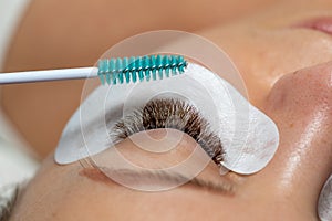 Close Woman Eye with Eyelashes Extension with eyepatch under eye and brush for care after beauty treatment