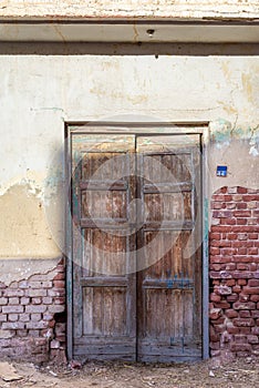 Closed abandoned wooden weathered door and shabby old grunge red bricks wall
