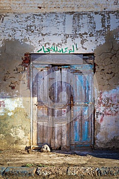 Closed abandoned wooden weathered door and shabby old grunge wall