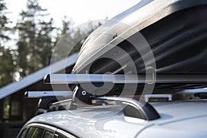 Closed assembled, roomy trunk or cargo box on the roof of the car, before a family vacation, amid a house and trees, on a summer photo