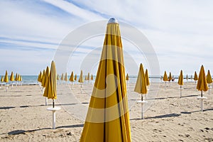 Closed beach umbrellas and cloudy sky