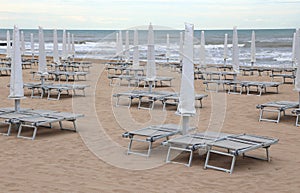 closed beach umbrellas and sun loungers on the sandy beach in wi