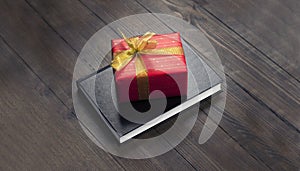 Closed Bible. Book. Gift in a red package with a gold bow. On a wooden table.