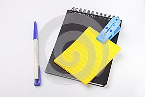 Closed black cover notebook ,yellow empty post note and pen