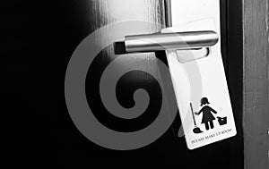 Closed black door of hotel room with please make up room sign on door handle