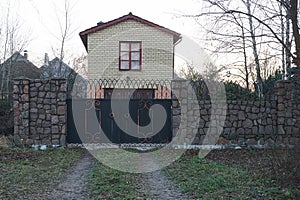 Closed black iron gate on a gray stone wall