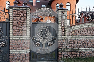 Closed black metal door with a gray wrought iron pattern and part of the stone wall