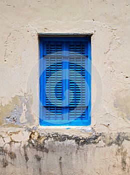 Closed blue window with shutters in the window opening of an old building or house