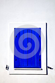 Closed blue window on a white wall in cycladic style photo