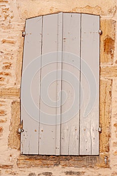 Tall, closed, gray, wood shutters on 1500s limestone building photo