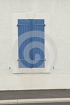 Closed blue wooden blinds on a white wall