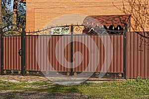 closed brown metal gate and closed door and part of the fence