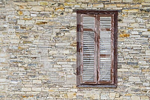 ÃÂ¡losed brown shuttered window in the wall of the light artificial stone