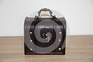 Closed brown treasure chest on a wooden surface