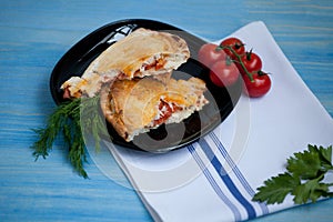 Closed calzone pizza on a wooden table with fresh tomatoes and d