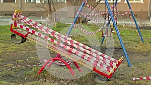 Closed children Playground in a residential area with swings is wrapped in red banning ribbons