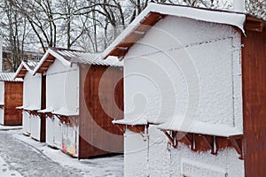 Closed Christmas market at winter snowy day. Wooden stalls with locks covered with snow.