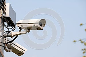 Closed-circuit camera attach on top of pole in park or public area for security reason with clear sky as background