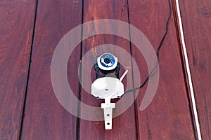 Closed-circuit camera, small CCTV attached to wall of brown wooden house.
