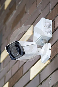 Closed-circuit television camera mounted on brick wall. CCTV security camera outdoors