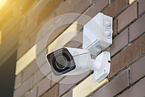 Closed-circuit television camera mounted on brick wall. CCTV security camera outdoors