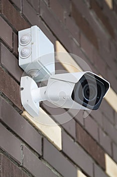 Closed-circuit television camera mounted on brick wall. CCTV security camera outdoors