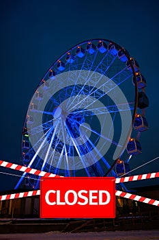 Closed due to a pandemic. Passage to ferris wheel is blocked by red and white ribbon and sign hanging is closed.