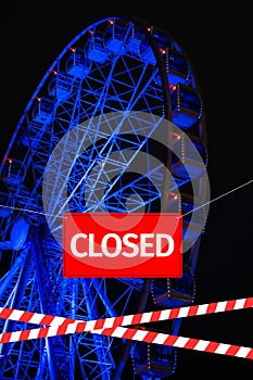 Closed due to a pandemic. Passage to ferris wheel is blocked by red and white ribbon and sign hanging is closed.