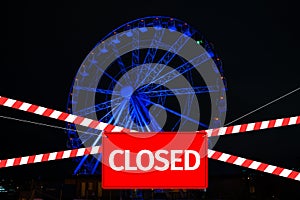 Closed due to a pandemic. Passage to ferris wheel is blocked by red and white ribbon and sign hanging is closed.