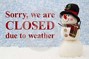 Closed due to weather sign with snowman and snow with snowy sky