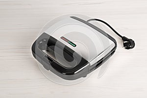 Closed electric sandwich maker on white wooden table
