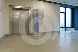 Closed elevator doors. Shiny metal elevator doors in a new modern elevator. An empty hall on the floor of an office building