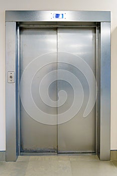 Closed elevator doors. Shiny metal elevator doors in a new modern elevator. An empty hall on the floor of an office building