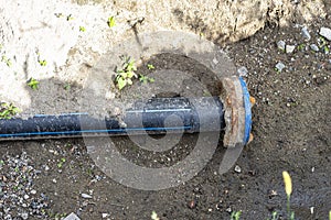 Closed end of a plastic water pipe lying along a ditch with high groundwater, water connection on the estate.