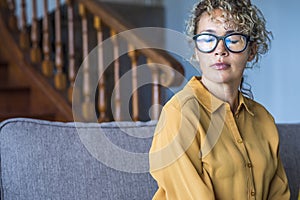 Closed eyes portrait sad expression young adult woman sitting alone on the sofa - depression disease and loneliness for caucasian