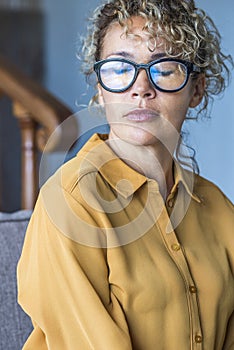 Closed eyes portrait sad expression young adult woman sitting alone on the sofa - depression disease and loneliness for caucasian