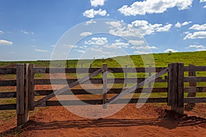 Closed farm gate under blue sky with clouds