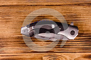 Closed folding knife on a wooden table. Top view