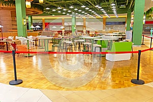 Closed food courts empty tables and chairs in catering and fast wood areas sealed and fenced in by red flight deck, coronavirus