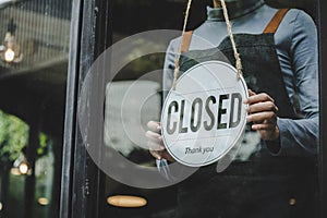 Closed. friendly waitress wearing protection face mask turning open sign board on glass door in modern cafe coffee shop, cafe rest