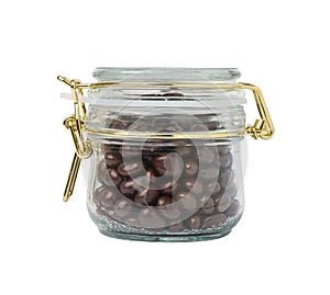 Closed glass jar with dragee chocolate-covered raisins, isolated on white background