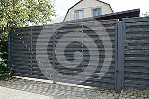 Closed gray private gate and wooden plank fence