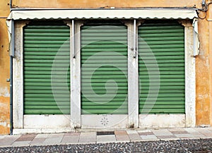 Closed green metal rolling shutters on an old building